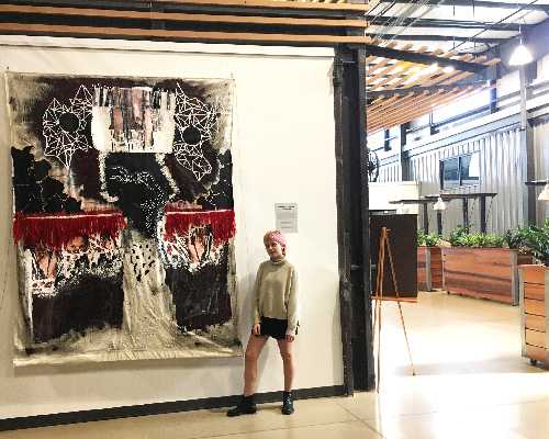 warwick art student poses next to work